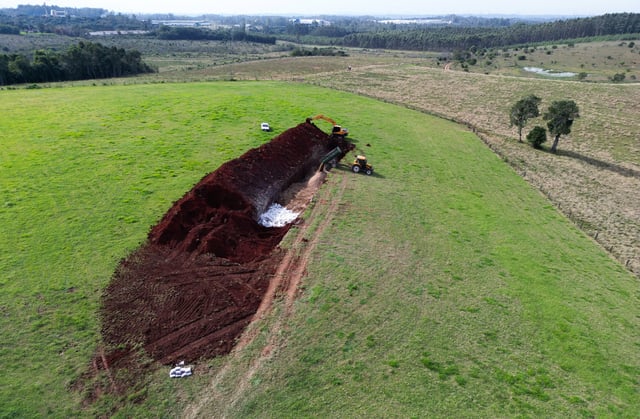 A drone view shows an excavator moving earth next to a hole in the ground at a poultry farm, after Brazil confirmed its first outbreak of bird flu on Friday, triggering protocols for a country-wide trade ban from top buyer China and state-wide restrictions for other major consumers, in Montenegro, Brazil May 17, 2025. REUTERS/Diego Vara