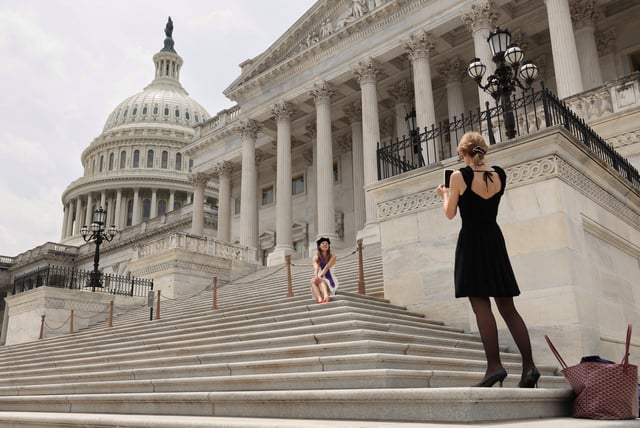 A graduate has her photo taken at the U.S. Capitol on the day U.S. President Donald Trump's sweeping tax bill failed to clear a key procedural hurdle as hardline Republicans demanding deeper spending cuts blocked the measure in a rare political setback for the Republican president in Congress, in Washington, D.C., U.S., May 16, 2025. REUTERS/Kevin Lamarque