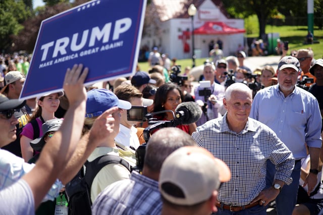 Republican U.S. Presidential candidate and former Vice President Mike Pence speaks to members of the press as a Trump supporter holds up a Trump campaign sign at the Iowa State Fair on August 11, 2023 in Des Moines, Iowa.