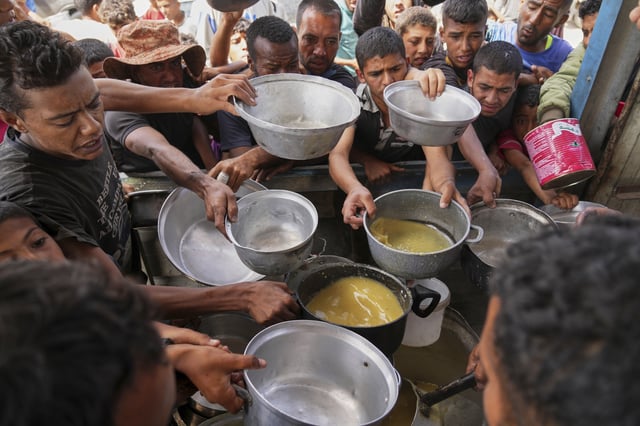 Palestinians struggle to receive cooked food distributed at a community kitchen in Khan Younis, southern Gaza Strip, Wednesday, May 14, 2025. (AP Photo/Abdel Kareem Hana)