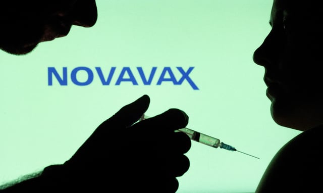 People pose with syringe with needle in front of displayed Novavax logo in this illustration taken, December 11, 2021. REUTERS/Dado Ruvic/Illustration/File Photo
