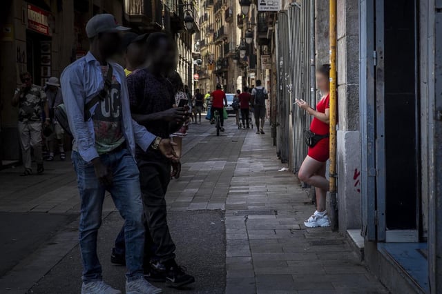 Una prostituta esperando a clientes en un portal de la calle Robadors, en el barrio del Raval, en Barcelona.