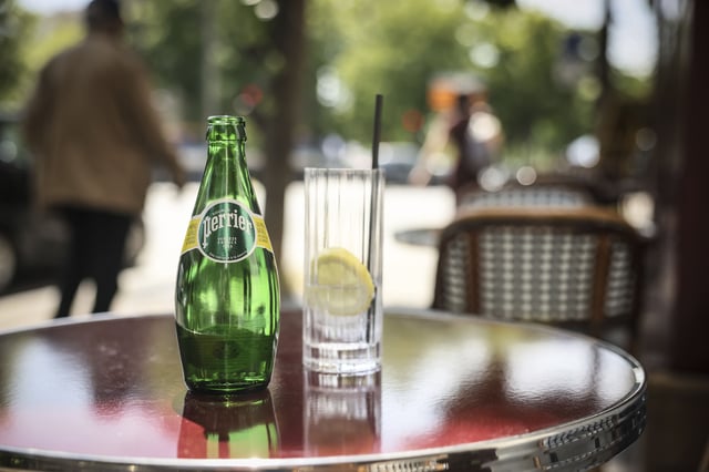 A bottle of Perrier stands on a cafe table as a French Senate inquiry commission said the government of President Emmanuel Macron covered up decisions over the illegal treatment of mineral water by food industry giant Nestle, Monday, May 19, 2025 in Paris. (AP Photo/Thomas Padilla)