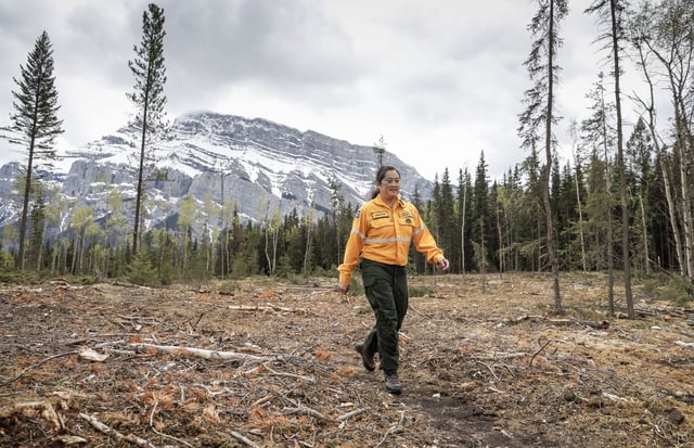 Jane Park, a fire and vegetation specialist with Parks Canada, walks through a newly constructed firebreak in Banff National Park, Alta., Thursday, May 15, 2025.THE CANADIAN PRESS/Jeff McIntosh