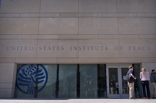 People stand outside the headquarters of the United States Institute of Peace, Tuesday, March 18, 2025, in Washington.