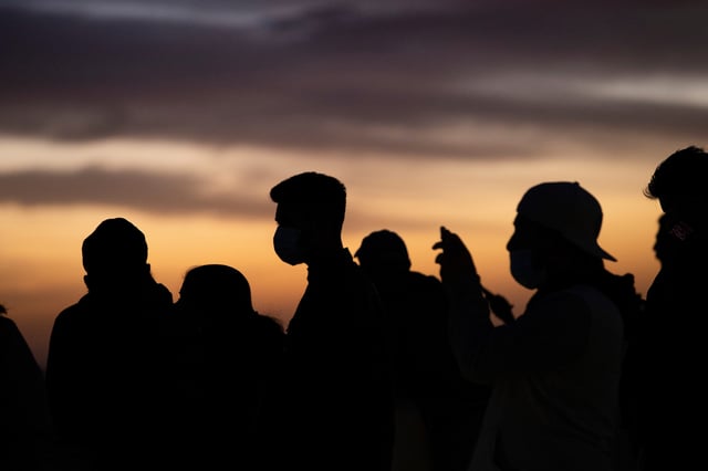 People wearing face protective masks watch the sunset from Griffith Observatory during a partial lockdown during the outbreak of the coronavirus disease (COVID-19), in Los Angeles, California, U.S., December 7, 2020. REUTERS/Mario Anzuoni/File Photo