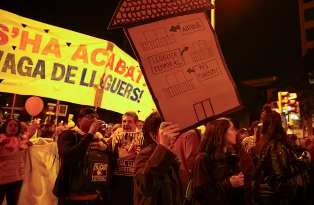 A demonstrator holds a house-shaped sign that reads "from touristic flat to temporary rent to Airbnb" during a protest to demand lower housing rental prices and better living conditions, in Barcelona, Spain, November 23, 2024.