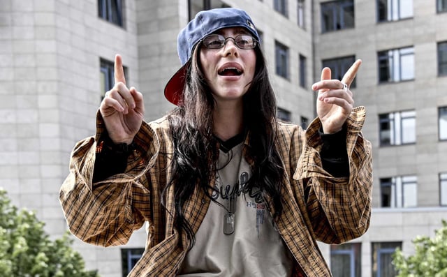 Billie Eilish is sitting on a ledge of a staircase railing known as the &#34;Billie Eilish wall&#34;, in Berlin on June 7, 2024.  Eilish has significantly extended her Hit Me Hard and Soft world tour, with new San Francisco dates set for Nov. 22–23. The announcement comes as Eilish addresses viral criticism of a Met Gala look she says was AI-generated. “I wasn’t even there,” she told fans on Instagram, 