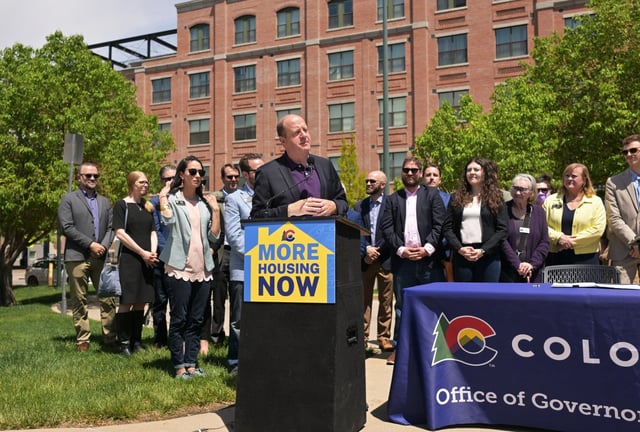 Colorado Gov. Jared Polis speaks to the media with lawmakers and advocates behind him before signing a priority land-use bill passed this session at the Evans light rail station in Denver on May 13, 2024. (Photo by RJ Sangosti/The Denver Post)