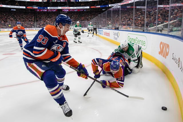 Dallas Stars' Jason Robertson (21) and Edmonton Oilers' Connor McDavid (97) battle as Ryan Nugent-Hopkins (93) picks up the loose puck during first period NHL action in Edmonton on Saturday, March 8, 2025. 