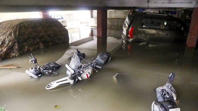 Vehicles partially submerged at the basement of an apartment following heavy rains, at Wilson Garden in Bengaluru, Monday, 