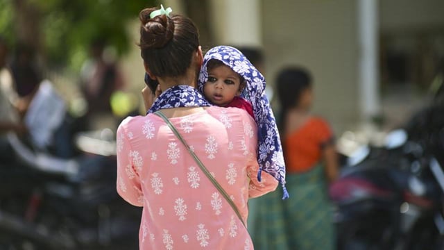 A woman shields her child from the scorching heat on a hot summer day in Prayagraj. (PTI Photo)
