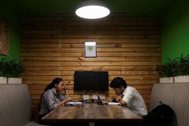 People sit and work on their laptops at Deloitte's office in Gurugram, India, June 13, 2023. REUTERS/Anushree Fadnavis/File Photo
