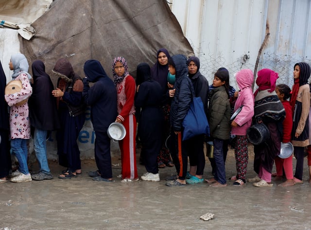 Palestinians queue to receive food cooked by a charity kitchen, amid a hunger crisis, as the Israel-Hamas conflict continues, in Khan Younis, southern Gaza Strip, November 24, 2024. REUTERS/Mohammed Salem/File Photo