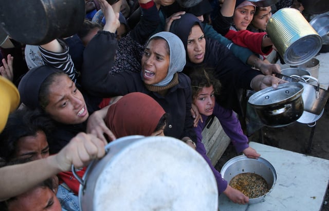 Palestinians gather to receive food cooked by a charity kitchen, amid a hunger crisis, as the Israel-Hamas conflict continues, in Khan Younis in the southern Gaza Strip, January 2, 2025. REUTERS/Hatem Khaled/File Photo