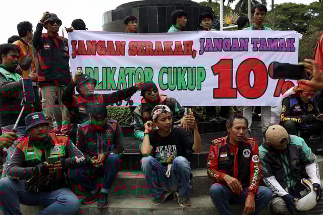 Motorcycle taxi drivers working for online ride-hailing start-ups carry a banner reading, "Don't be greedy, 10% is enough for the applicator", as they protest to lower the commission they pay, and demand higher pay in Jakarta, Indonesia May 20, 2025. REUTERS/Ajeng Dinar Ulfiana