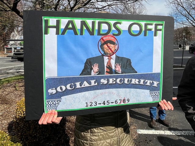 A person holds a sign during a protest against cuts made by U.S. President Donald Trump's administration to the Social Security Administration, in White Plains, New York, U.S., March 22, 2025. REUTERS/Nathan Layne/File Photo