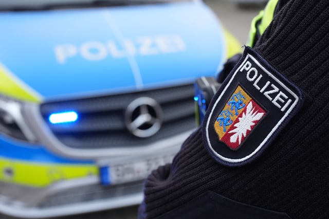 Ein Beamter der Polizei Schleswig-Holstein steht vor einem Einsatzfahrzeug. (Symbolbild)