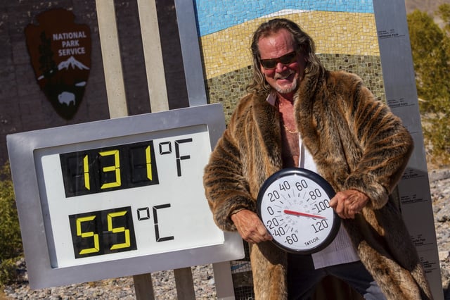 Thor Teigen poses in a fur jacket next to a thermometer displaying a temperature of 131 degrees Fahrenheit / 55 degrees Celsius at the Furnace Creek Visitors Center, in Death Valley National Park, Calif., Sunday, July 7, 2024.