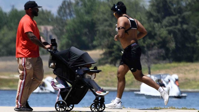 People push a baby stroller and jog in the heat Monday, May 19, 2025, at Lake Balboa in the Sepulveda Basin as a warm-up in temperatures continues in Southern California. In the background, people pedal swan boats on the artificial lake, which is filled with reclaimed water. (Photo by Gene Blevins, Contributing Photographer)