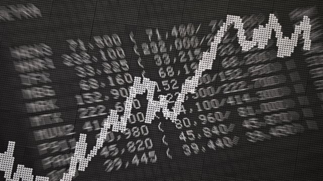 Eine Anzeigetafel mit Kursen von Unternehmen sowie der DAX-Kurve