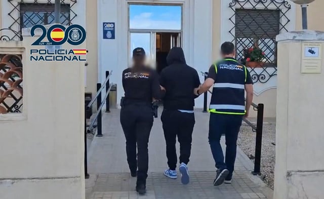 El detenido, custodiado por dos agentes de la Policía Nacional en la entrada a la comisaría de Dénia