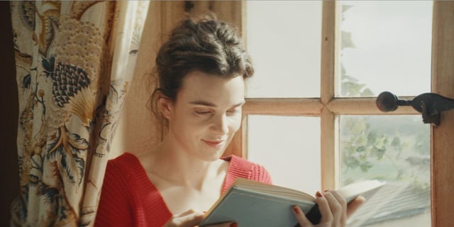 Camille Rutherford as Agathe Robinson reading and smiling in "Jane Austen Wrecked My Life"