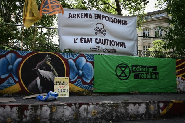 Une banderole indique "Arkema empoisonne, l'Etat soutient" lors d'un rassemblement devant le palais de justice de Lyon en soutien à des activistes poursuivis après une action anti-pollution en mars contre l'usine du chimiste Arkema, le 18 juin 2024