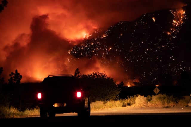 A motorist watches from a pullout on the Trans-Canada Highway as a wildfire burns on the side of a mountain in Lytton, B.C., Thursday, July 1, 2021. THE CANADIAN PRESS/Darryl Dyck