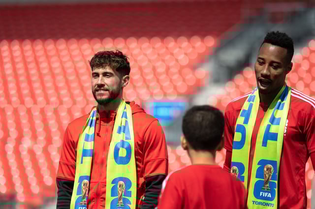 Jonathan Osorio, left to right, and Mark-Anthony Kaye, from Toronto FC and Canada’s national team, chats with a youth member during a media unveiling of the official brand and new #WeAre26 awareness campaign for FIFA World Cup 2026, at BMO Field in Toronto, the host city, on May 18, 2023.