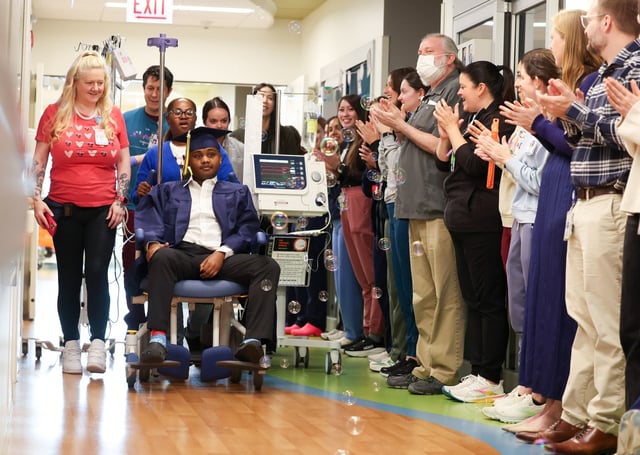Taevion Norris, 18, a senior at Leyden High School, West Campus, is wheeled down the hallway, dressed in graduation attire, at Lurie Children’s Hospital on May 21, 2025. Norris has been hospitalized due a heart condition since March 11 waiting for a heart transplant. (Stacey Wescott/Chicago Tribune)