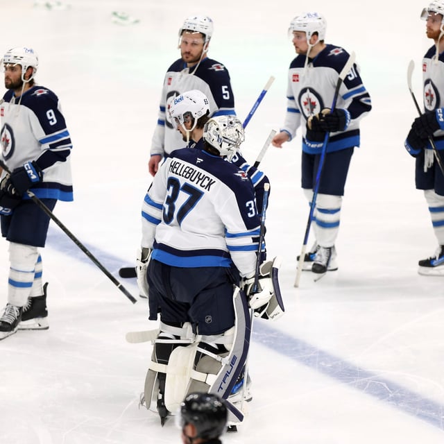 Winnipeg Jets' Connor Hellebuyck (37) and Mark Scheifele (55) join the hand shake line after their loss in overtime to the Dallas Stars in Game 6 of a second-round NHL hockey playoff series in Dallas, Saturday, May 17, 2025. (AP Photo/Gareth Patterson)