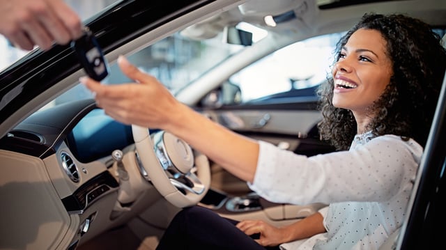 Car dealer is giving key for a new car to a woman
