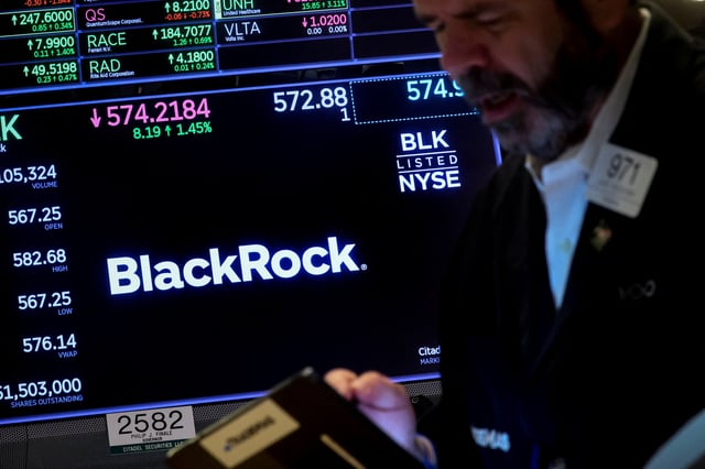 A trader works as a screen displays the trading information for BlackRock on the floor of the New York Stock Exchange (NYSE) in New York City, U.S., October 14, 2022. REUTERS/Brendan McDermid/File Photo