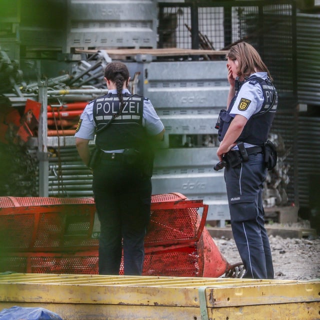 Einsatzkräfte der Polizei stehen auf der Hochbrücken-Baustelle neben der abgestürzten Gondel