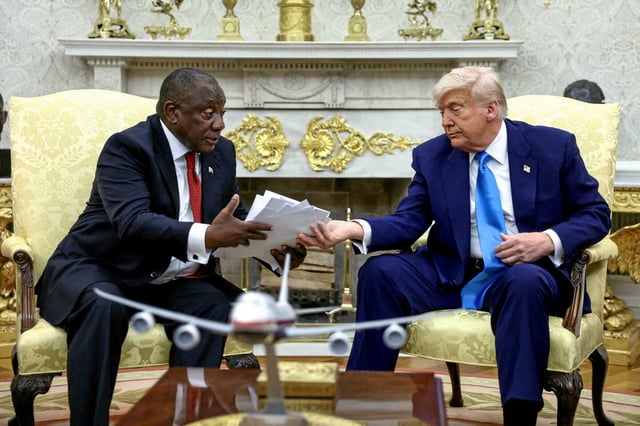 Donald Trump remet au président sud-africain Cyril Ramaphosa un article de presse qui, selon lui, montrent des Sud-Africains blancs tués, dans le bureau ovale de la Maison Blanche à Washington, D.C., États-Unis, le 21 mai 2025. 
