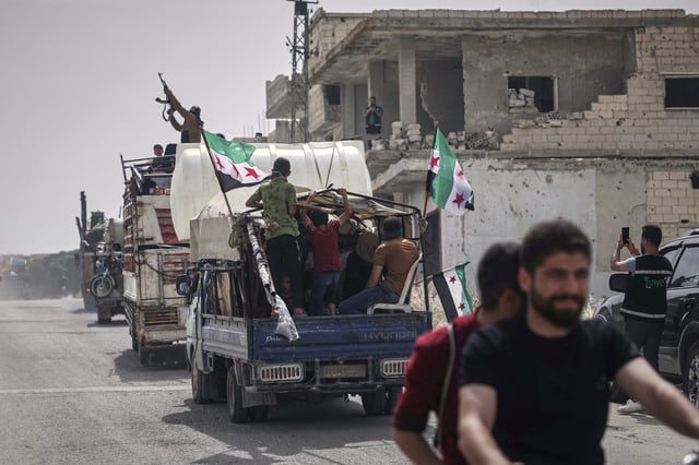 A man fires into the air from one of the trucks carrying some of the 60 displaced families who, supported by an NGO, are returning to their village after more than five years in the Atmeh camps near the Syrian-Turkish border, in Kafr Sijna, south of Idlib, Syria, Sunday, May 18, 2025. (AP Photo/Ghaith Alsayed)
