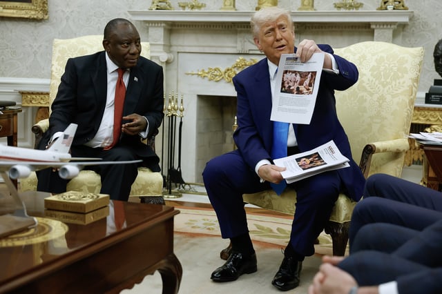 President Donald Trump holds up a printed article from 'American Thinker' while accusing South African President Cyril Ramaphosa of state-sanctioned violence against white farmers in South Africa during a press availability in the Oval Office on May 21, 2025. (Photo by Chip Somodevilla/Getty Images)