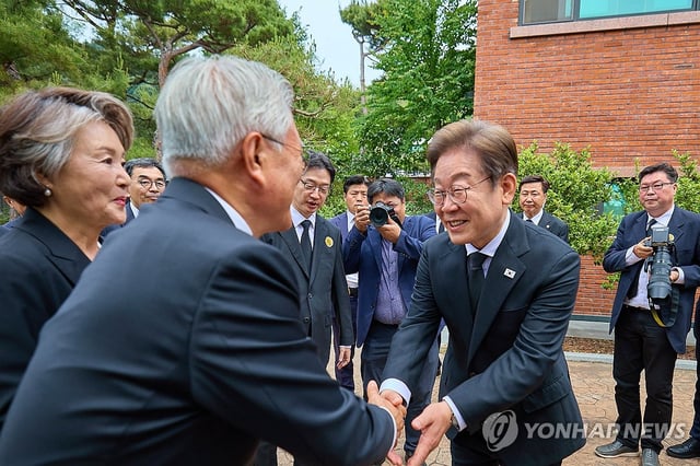 Democratic Party presidential candidate Lee Jae-myung (R) shakes hands with former President Moon Jae-in during a memorial service marking the 16th anniversary of the death of former President Roh Moo-hyun in the rural village of Bongha in Gimhae, southeastern South Korea, on May 23, 2025, in this photo provided by Lee's party. (PHOTO NOT FOR SALE) (Yonhap)