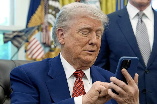 Donald Trump coupe son portable qui a sonné deux fois alors qu'il parlait aux journalistes après avoir signé des décrets exécutifs concernant l'énergie nucléaire dans le bureau ovale de la Maison Blanche, vendredi 23 mai 2025, à Washington.
