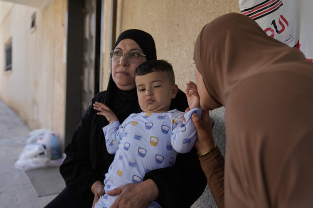 Palestinian Hazar Estity kisses her 21-month-old son, Nizar, who is being held by his grandmother, Nazek, on April 29, 2025, at an apartment in the West Bank town of Zababdeh. Estity says she was used as a human shield by Israeli soldiers. (AP Photo/Nasser Nasser)