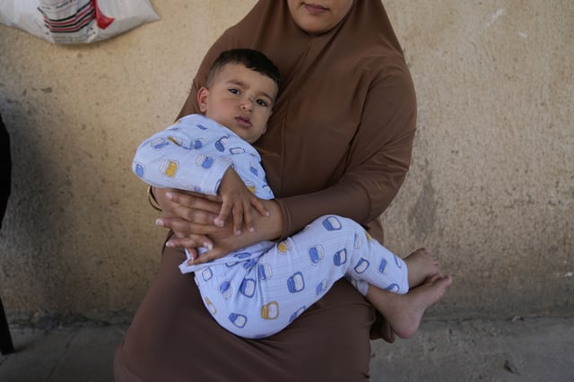 Palestinian Hazar Estity holds her 21-month-old son, Nizar, on April 29, 2025, in the West Bank town of Zababdeh, where they fled when the Jenin refugee camp was raided by the Israeli army. Estity says she was used as a human shield by Israeli soldiers there. (AP Photo/Nasser Nasser)