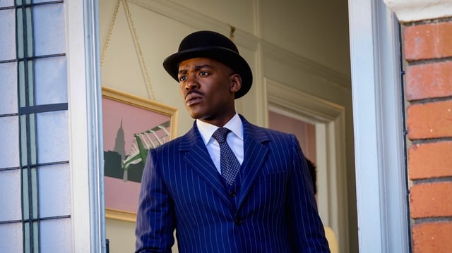 The Doctor in a pinstripe suit and bowler hat.