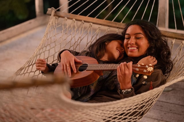 Lilo (Maia Kealoha, left) and sister Nani (Sydney Agudong) sing and play ukulele on a hammock in "Lilo and Stitch."