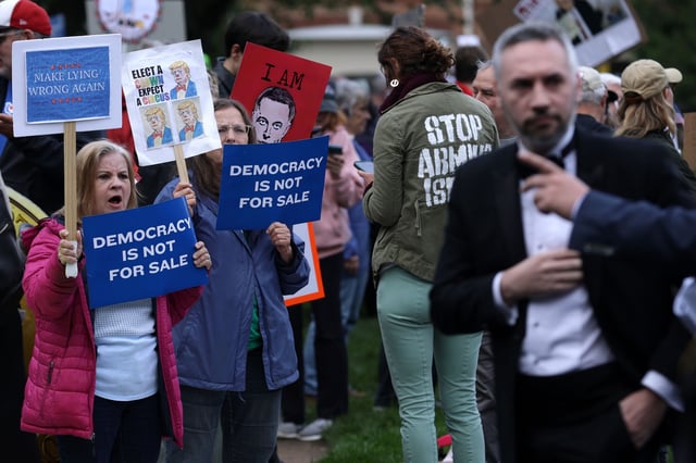 Demonstrators protest as a guest arrives outside Trump National Golf Club, where the top 220 holders of the president’s personal $TRUMP meme coin were invited to private dinner.