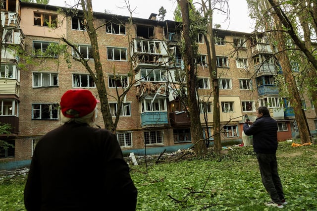 Residents look at an apartment building in Kyiv, Ukraine, that was damaged during a Russian attack, on Saturday.