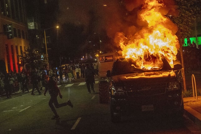 A demonstrator runs away from a burning car May 30, 2020, one block from the White House.