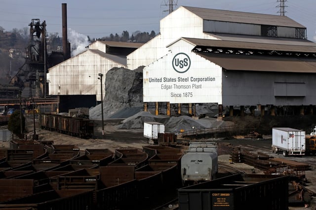 Die Hallen eines Stahlwerkes, im Vordergrund Gleise mit Güterwaggons
