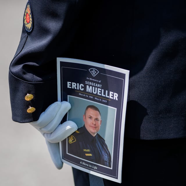 A member of the Ontario Provincial Police holds a program during the funeral of Ontario Provincial Police Sgt. Eric Mueller in Ottawa, on Thursday, May 18, 2023. THE CANADIAN PRESS/Spencer Colby