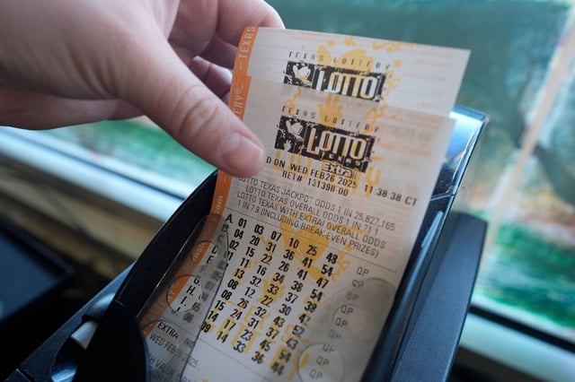 A customer grabs printed tickets from a Texas Lottery sales terminal at Fuel City in Dallas, Wednesday, Feb. 26, 2025.